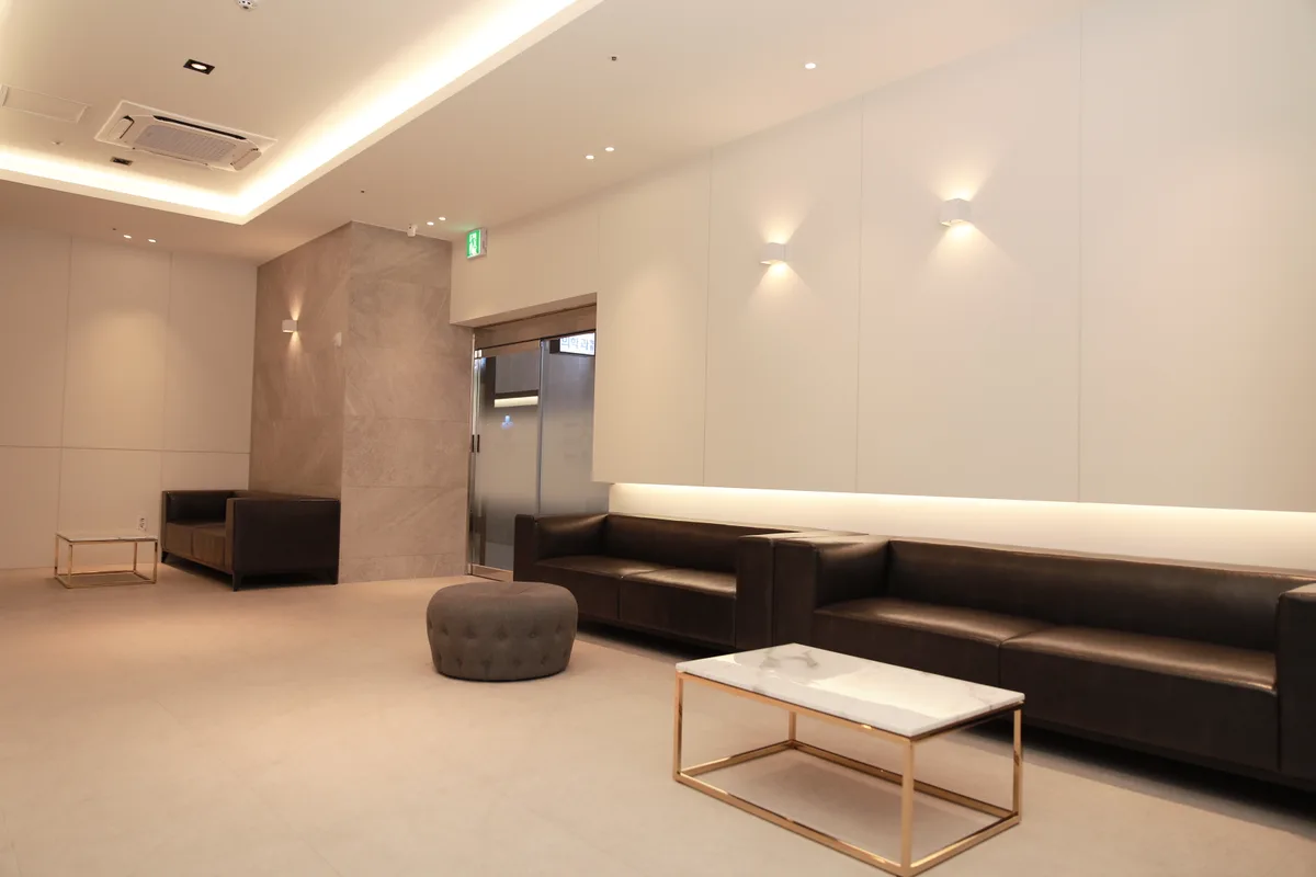 Waiting room at Geudaegoun Dermatology Clinic, showing a lobby with beige tile flooring and leather sofas
